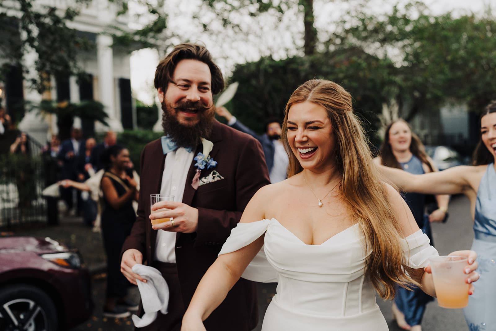 bride and bridesmaids walk down the sidewalk of a busy city
